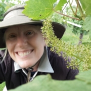 selfie of June with grape cluster blooming in vineyard