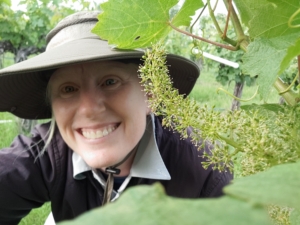 selfie of June with grape cluster blooming in vineyard
